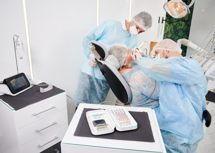Dentists performing a same-day dental implant procedure using advanced equipment at a modern dental implant clinic.
