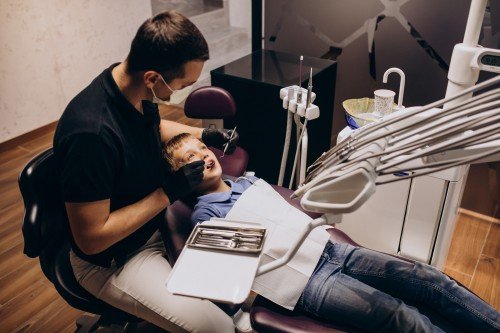 Dentist examining a young boy’s teeth during a dental checkup in a modern dental clinic